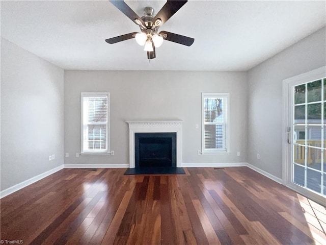 unfurnished living room with a wealth of natural light, a fireplace with flush hearth, and dark wood finished floors