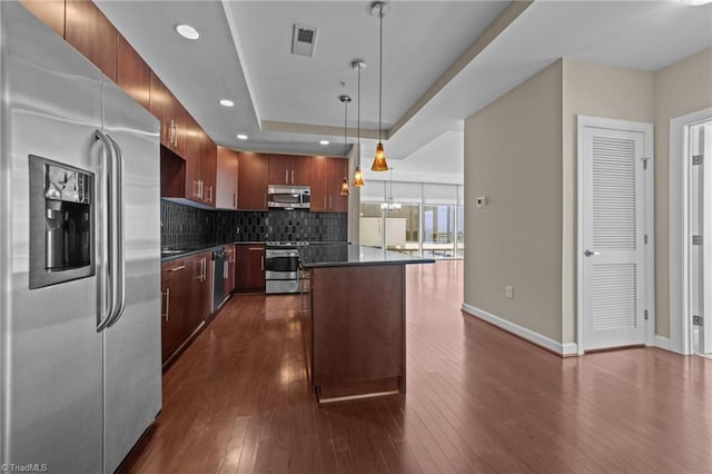 201 N Elm St Unit 703, Greensboro, NC 27401 - kitchen featuring appliances with stainless steel finishes, dark countertops, a center island, backsplash, and baseboards