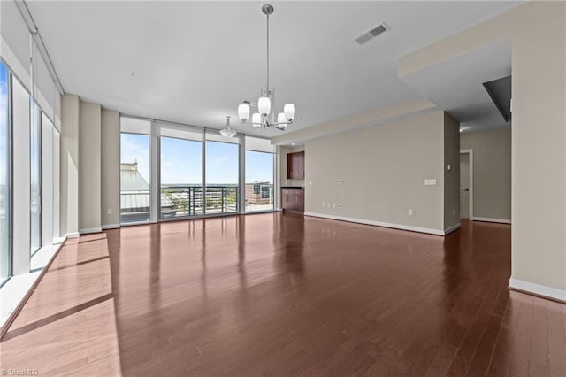 201 N Elm St Unit 703, Greensboro, NC 27401 - empty room featuring floor to ceiling windows, a chandelier, wood finished floors, and baseboards