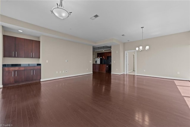 201 N Elm St Unit 703, Greensboro, NC 27401 - unfurnished living room featuring a chandelier, dark wood finished floors, and baseboards