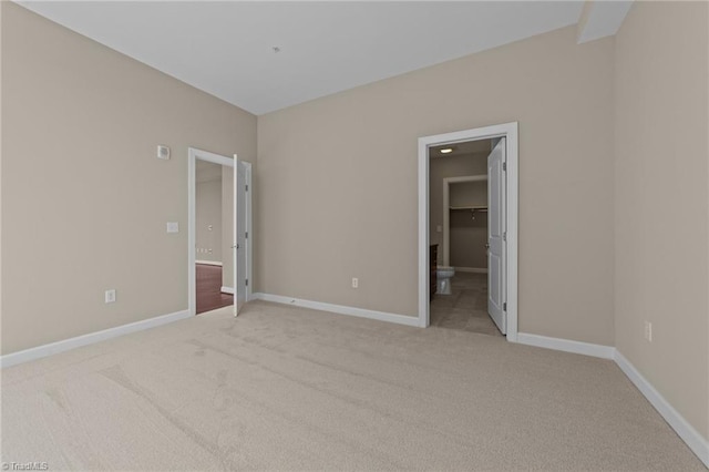 201 N Elm St Unit 703, Greensboro, NC 27401 - unfurnished bedroom featuring a walk in closet, light carpet, and baseboards