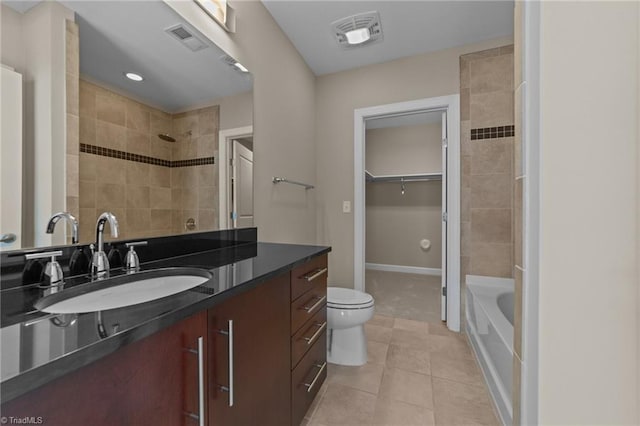 201 N Elm St Unit 703, Greensboro, NC 27401 - bathroom with a tile shower, tile patterned flooring, vanity, toilet, and a walk in closet