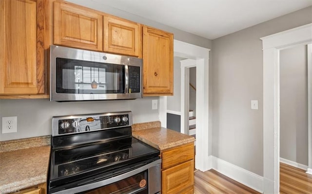 kitchen featuring light stone counters, light hardwood / wood-style floors, and stainless steel appliances