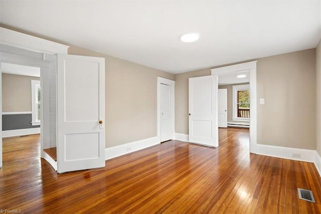 empty room featuring hardwood / wood-style floors and a baseboard heating unit