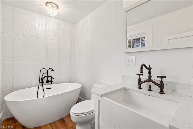 bathroom featuring toilet, tile walls, hardwood / wood-style flooring, a bathtub, and vanity