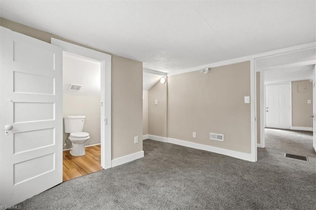 unfurnished bedroom featuring connected bathroom and dark colored carpet