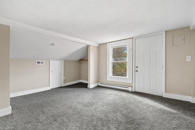 additional living space with a textured ceiling, vaulted ceiling, dark carpet, and a baseboard heating unit