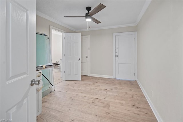 interior space with ornamental molding, a barn door, ceiling fan, and light hardwood / wood-style flooring