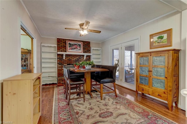 dining room featuring a textured ceiling, ornamental molding, ceiling fan, and wood-type flooring