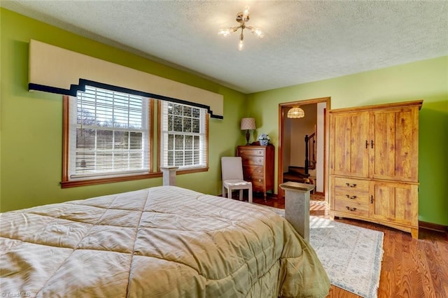 bedroom with wood-type flooring, a spacious closet, and a textured ceiling