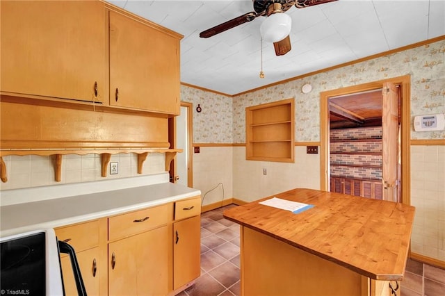 kitchen with stove, crown molding, a center island, and butcher block counters