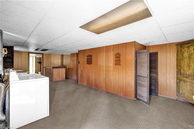 basement featuring washer / dryer, wood walls, and a drop ceiling