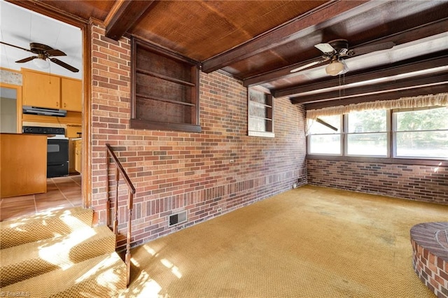 unfurnished living room with ceiling fan, wooden ceiling, beamed ceiling, brick wall, and light tile patterned floors