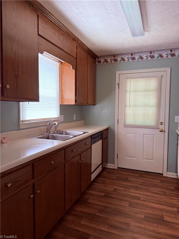 1770 Inglebrook Trl, Mount Airy, NC 27030 - kitchen with dishwashing machine, a sink, dark wood-style flooring, light countertops, and a textured ceiling