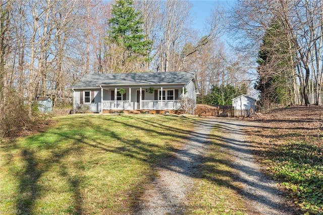 view of front of property with a porch, driveway, a front lawn, and fence