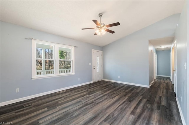 empty room featuring dark wood finished floors, vaulted ceiling, baseboards, and ceiling fan