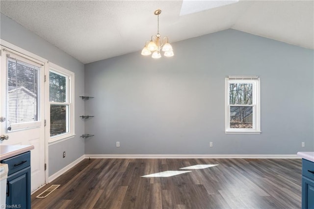 unfurnished dining area featuring baseboards, lofted ceiling, dark wood-style flooring, a textured ceiling, and a notable chandelier