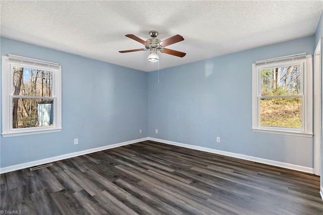 spare room with visible vents, a textured ceiling, dark wood finished floors, baseboards, and ceiling fan