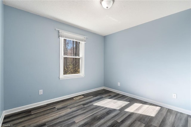 empty room with a textured ceiling, baseboards, and wood finished floors