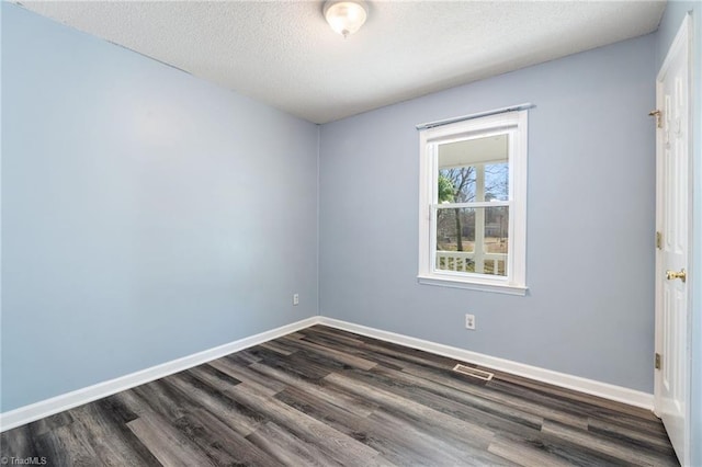 unfurnished room featuring visible vents, baseboards, a textured ceiling, and dark wood finished floors