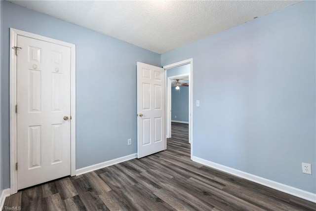 unfurnished bedroom featuring dark wood finished floors, a textured ceiling, and baseboards