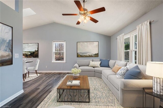 living room featuring baseboards, dark wood finished floors, vaulted ceiling, a textured ceiling, and a ceiling fan