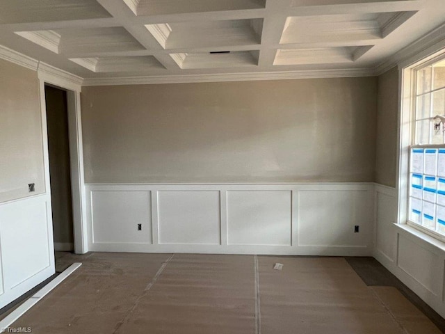 empty room with a healthy amount of sunlight, a wainscoted wall, and coffered ceiling