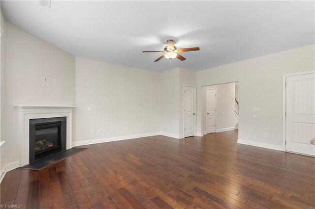 unfurnished living room with a ceiling fan, baseboards, a glass covered fireplace, and hardwood / wood-style flooring
