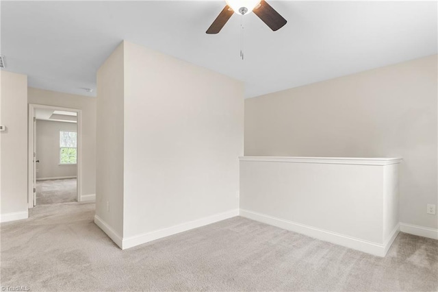 carpeted spare room with ceiling fan and baseboards
