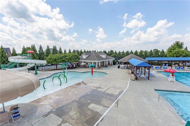 pool featuring a water play area, a patio, and a water slide