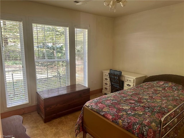 bedroom featuring ceiling fan, light tile patterned floors, and multiple windows