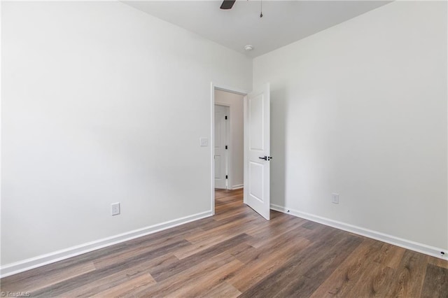 unfurnished room featuring dark wood-style flooring, ceiling fan, and baseboards