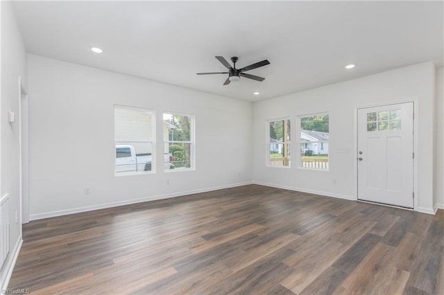 unfurnished living room featuring baseboards, dark wood-type flooring, plenty of natural light, and recessed lighting