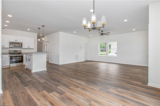 unfurnished living room with recessed lighting, ceiling fan with notable chandelier, wood finished floors, visible vents, and baseboards