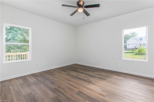 spare room featuring a ceiling fan, baseboards, and dark wood-type flooring