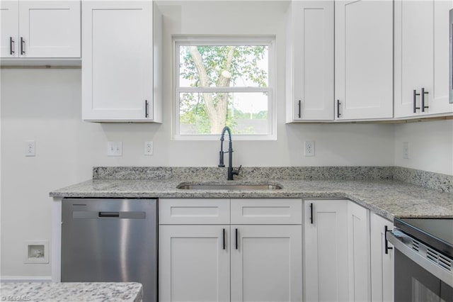 kitchen with light stone counters, stainless steel dishwasher, a sink, and white cabinetry