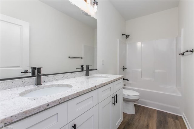 bathroom with bathtub / shower combination, double vanity, a sink, and wood finished floors