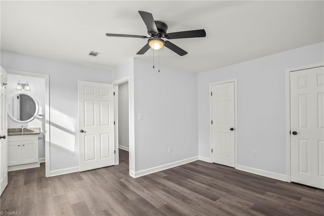 unfurnished bedroom featuring sink, ensuite bath, dark hardwood / wood-style floors, and ceiling fan