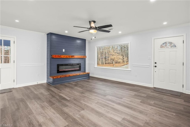 unfurnished living room featuring crown molding, wood-type flooring, ceiling fan, and a fireplace