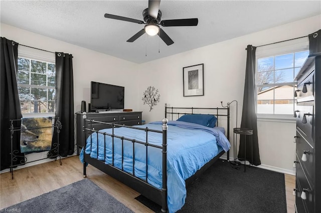 bedroom featuring ceiling fan, light hardwood / wood-style floors, and a textured ceiling