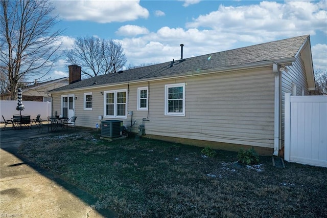 rear view of house with a patio, central AC, and a lawn