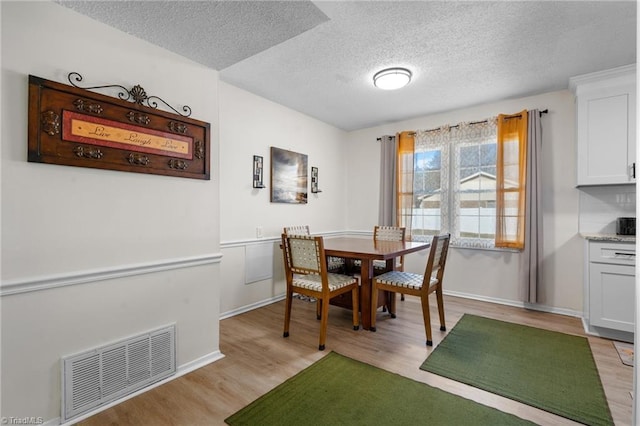 dining space featuring light hardwood / wood-style floors and a textured ceiling