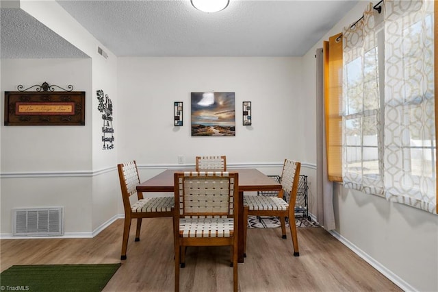 dining area with a wealth of natural light, light hardwood / wood-style flooring, and a textured ceiling