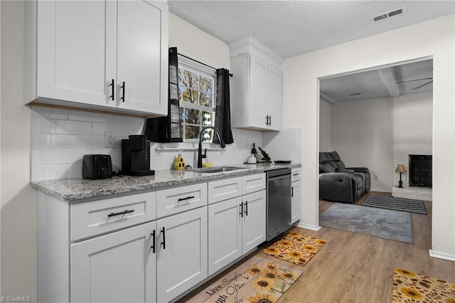 kitchen with white cabinets, a textured ceiling, light hardwood / wood-style floors, and stainless steel dishwasher