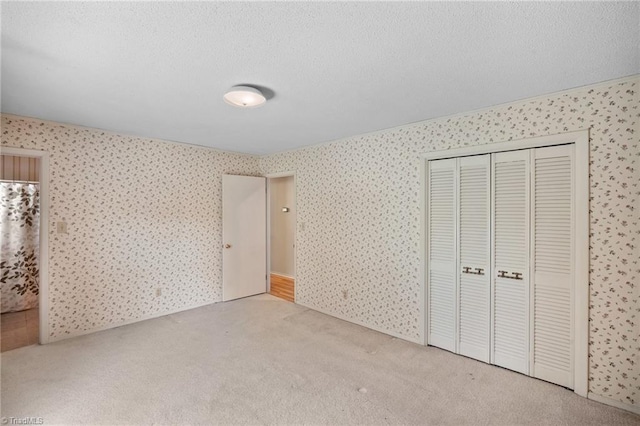 4904 Kacia Ct, Greensboro, NC 27407 - unfurnished bedroom featuring carpet flooring, a textured ceiling, wallpapered walls, and a closet