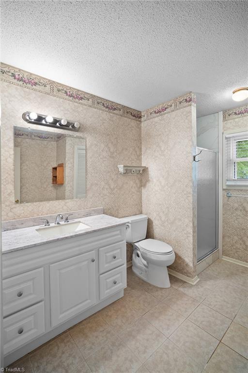 4904 Kacia Ct, Greensboro, NC 27407 - full bath featuring vanity, tile patterned flooring, toilet, a textured ceiling, and a stall shower