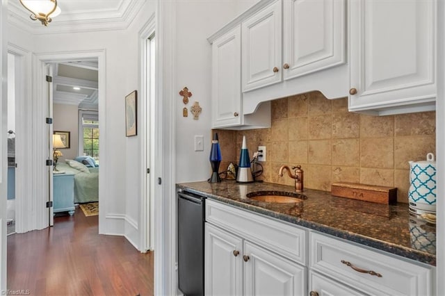 kitchen featuring sink, ornamental molding, dark hardwood / wood-style floors, white cabinetry, and dark stone countertops