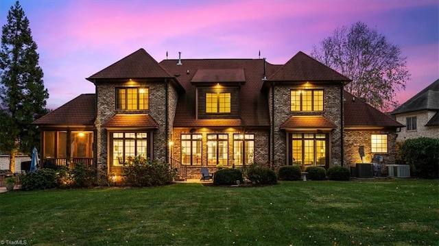 back house at dusk with central AC and a yard