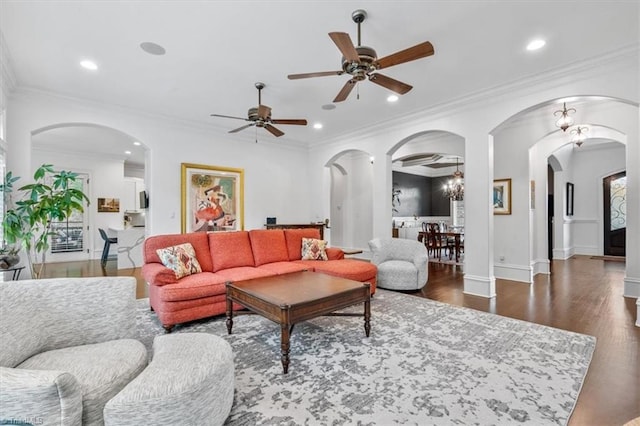 living room featuring ceiling fan with notable chandelier, dark hardwood / wood-style floors, and crown molding