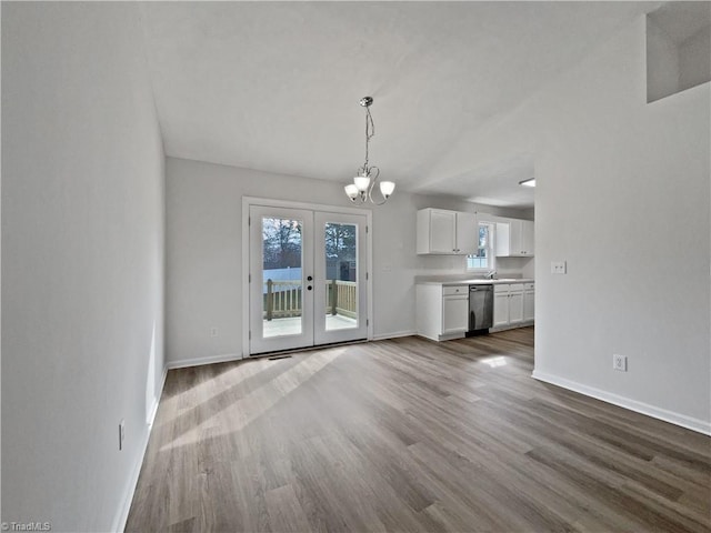 unfurnished living room with baseboards, french doors, an inviting chandelier, wood finished floors, and a sink